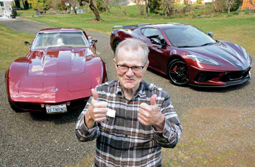 a person with two chevrolet corvettes