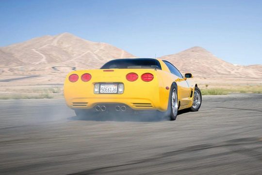 a yellow sports car on a test track with mountains